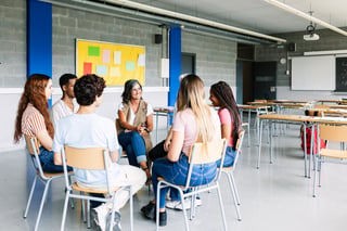 Teenage students discussing in classroom with teacher, education concept