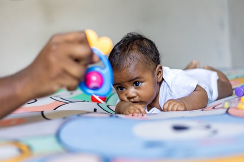 A little girl doing tummy time early stimulation development activities