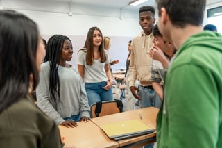 High school students collaborating discussing ideas in classroom