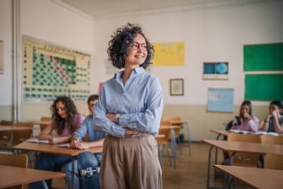 Confident female teacher in elementary classroom with engaged attentive students