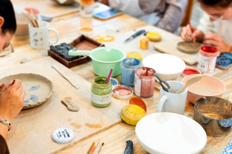 Busy hands working at a pottery studio, decorating ceramic plates with paint and tools